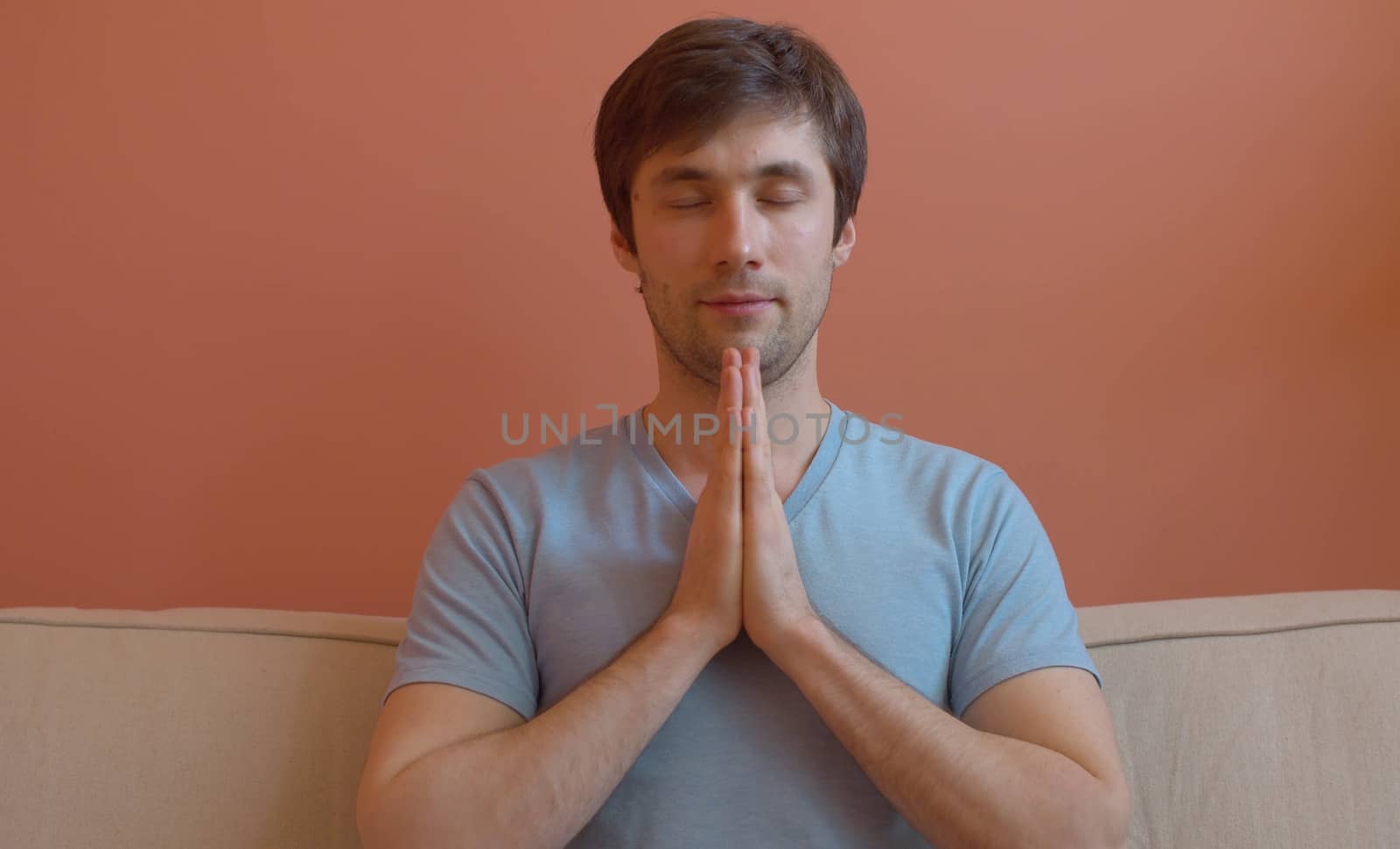 Portrait of young meditating man on pink background. Close up. The concept of meditation, relaxation, yoga, stress relief and inner peace and quiet