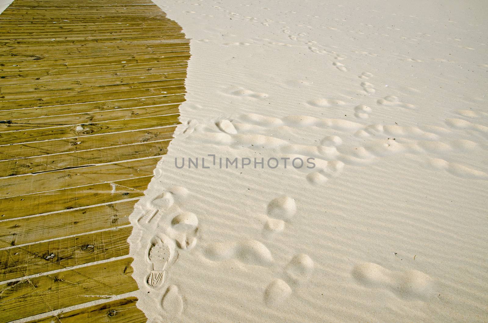 Sandy beach encroaching on a wooden boardwalk.  Monte Gordo seaside resort, Algarve Coast, Portugal.