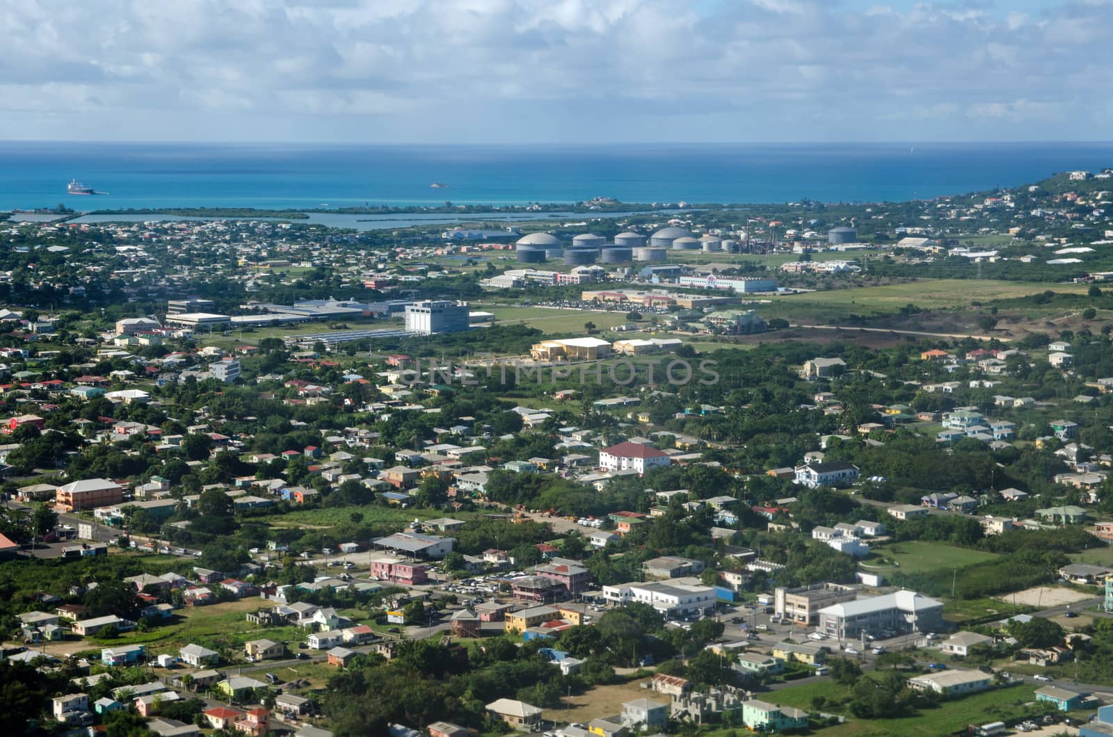 Aerial view of the city of St John's, Antigua and Barbuda looking across houses towards several shopping malls and the West Indies Oil Company terminal and the Caribbean Sea beyond on a sunny January day.