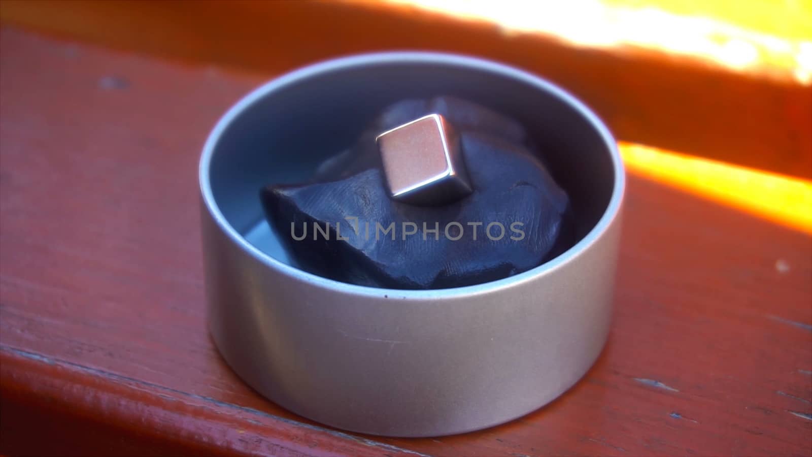 Metal cube falls into black fused plasticine at sunny day, time lapse, close up by nolimit046