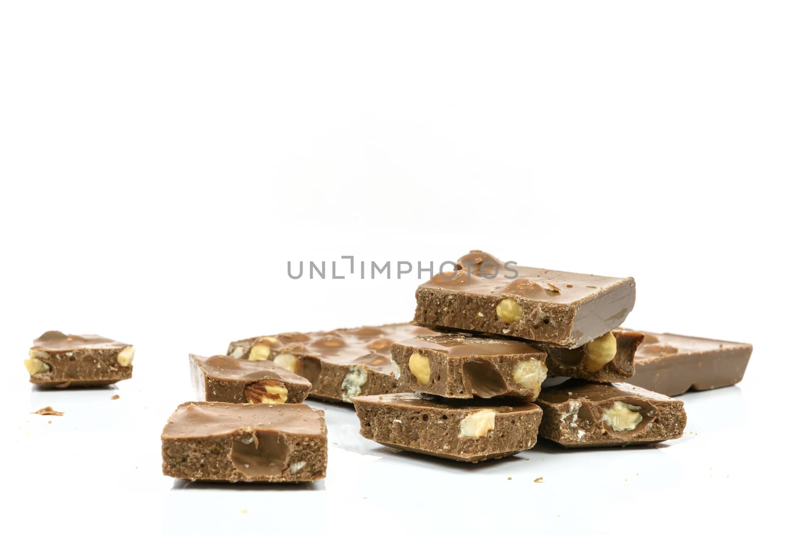 Stack of chocolate pieces with nuts in close-up and isolated on white background with copy space place.