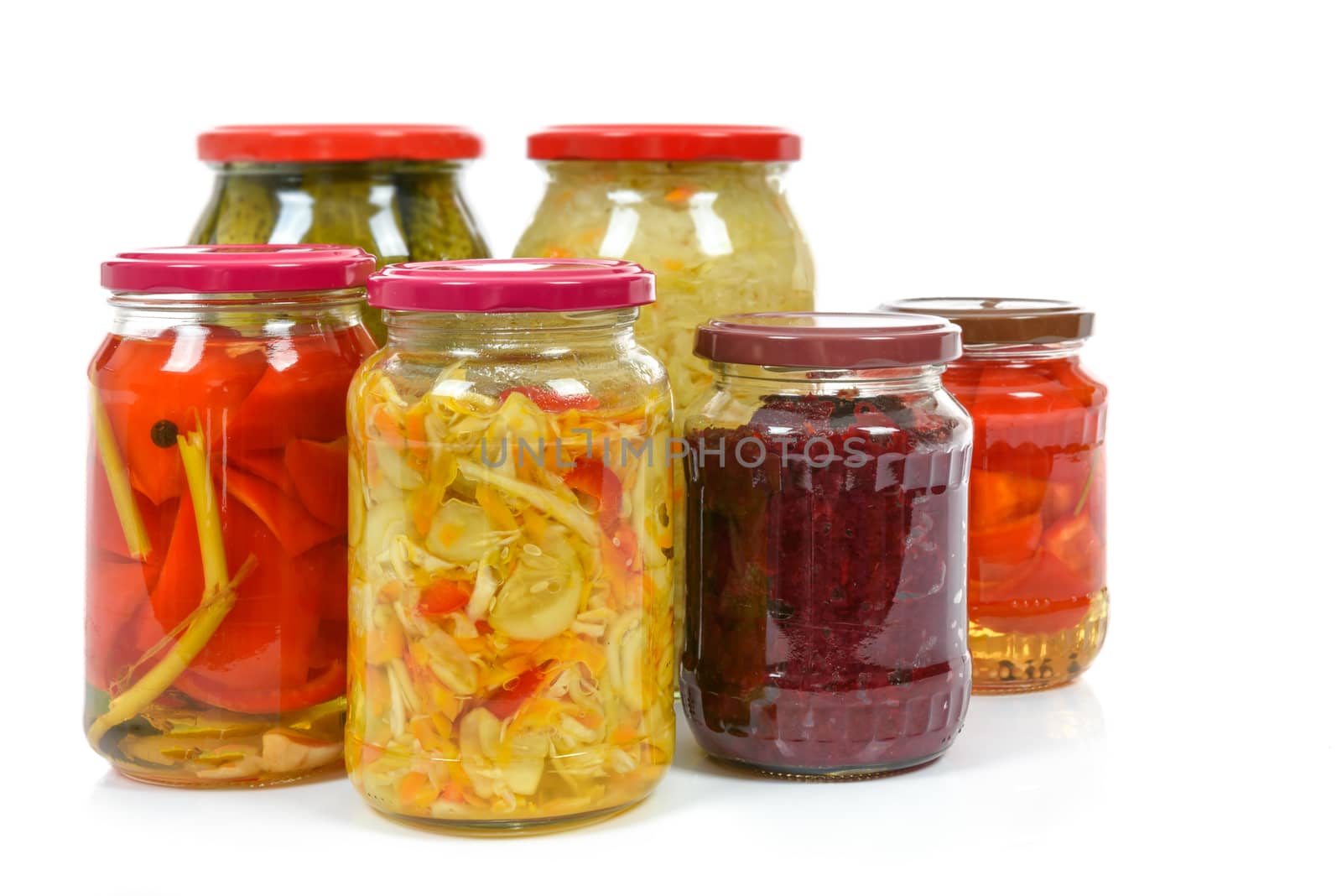 Jars with variety of homemade pickled vegetables isolated on a white background.