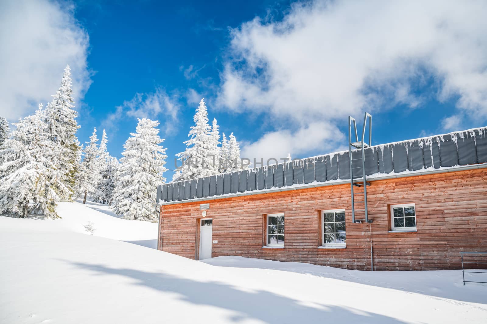 Snow covered wooden hut in the mountains.