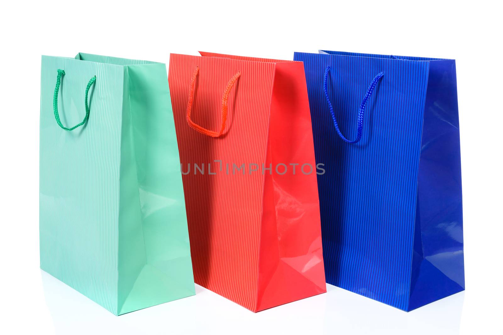 Three shopping bags in different colors in close up and isolated on a white background.