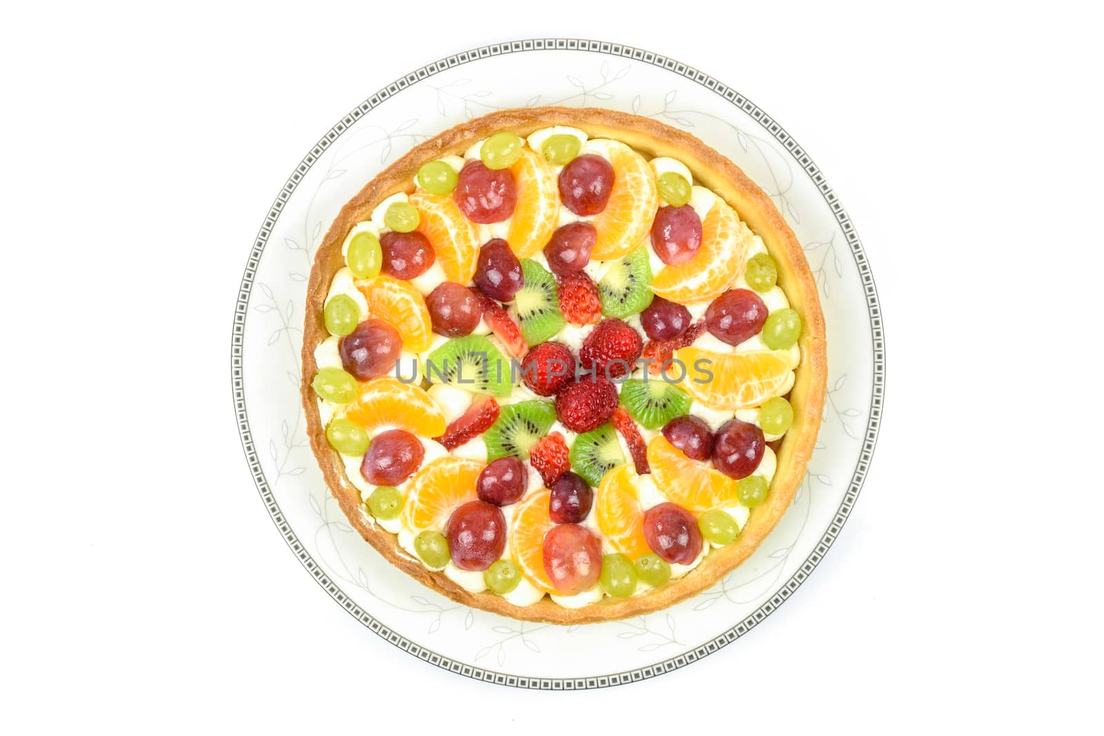 Top view of a fresh homemade multi-fruit tart cake on a plate and isolated on a white background.