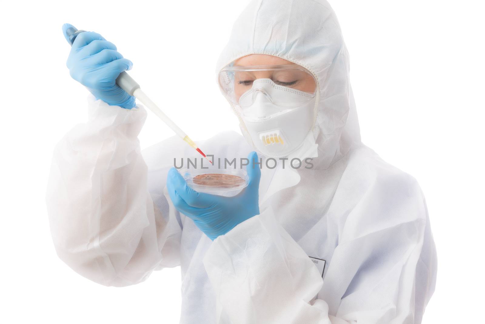 Female laboratory worker wearing protective hazmat biosecurity suit, gloves, respirator mask and goggles analyses samples