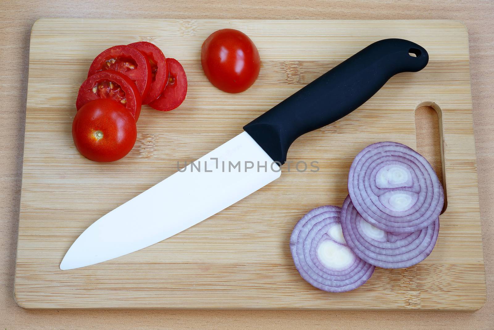 Ceramic knive with black handle on a wooden chopping board