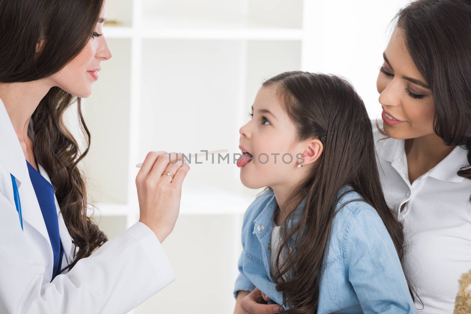 Little girl having throat examination by pediatrician at checkup in clinic