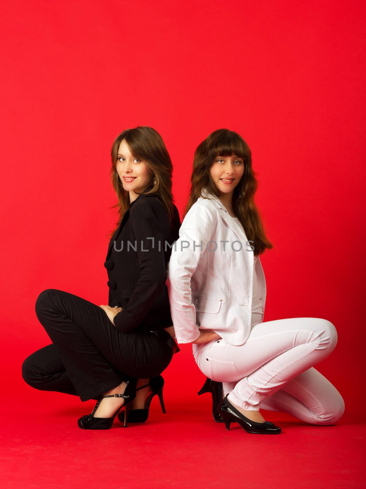 young pretty sisters twins posing sitting in studio