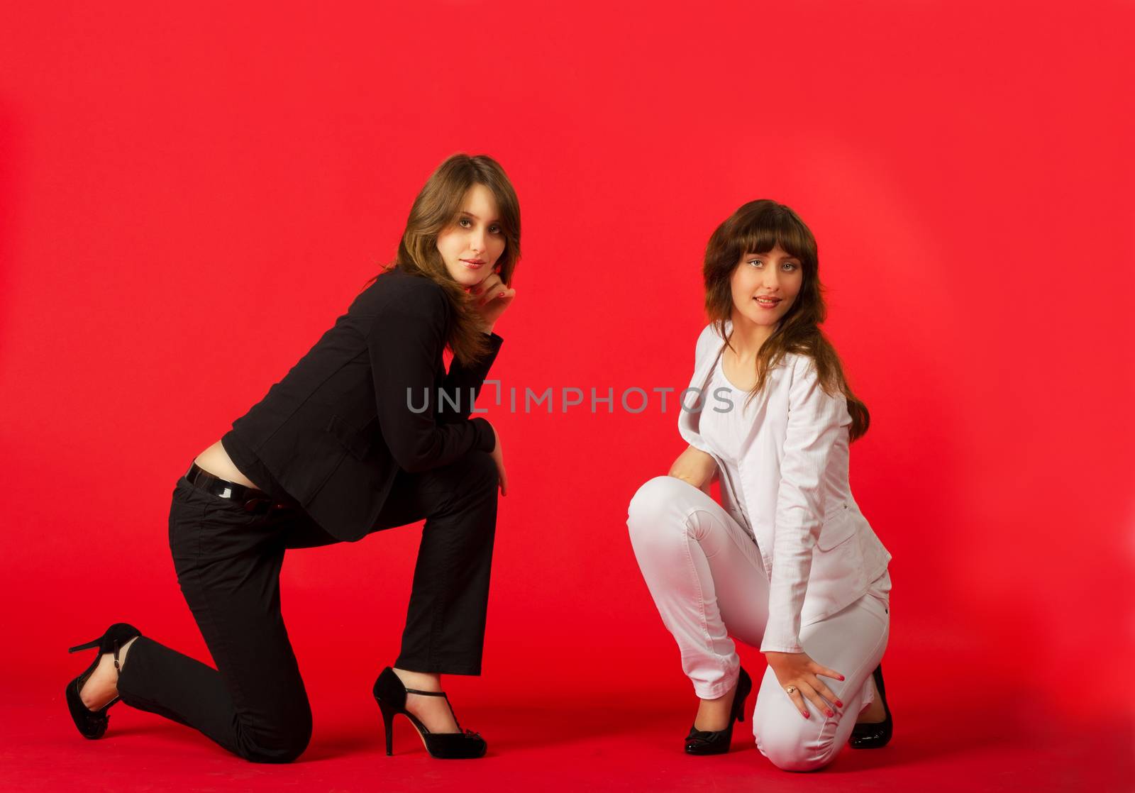 young pretty sisters twins posing sitting in studio