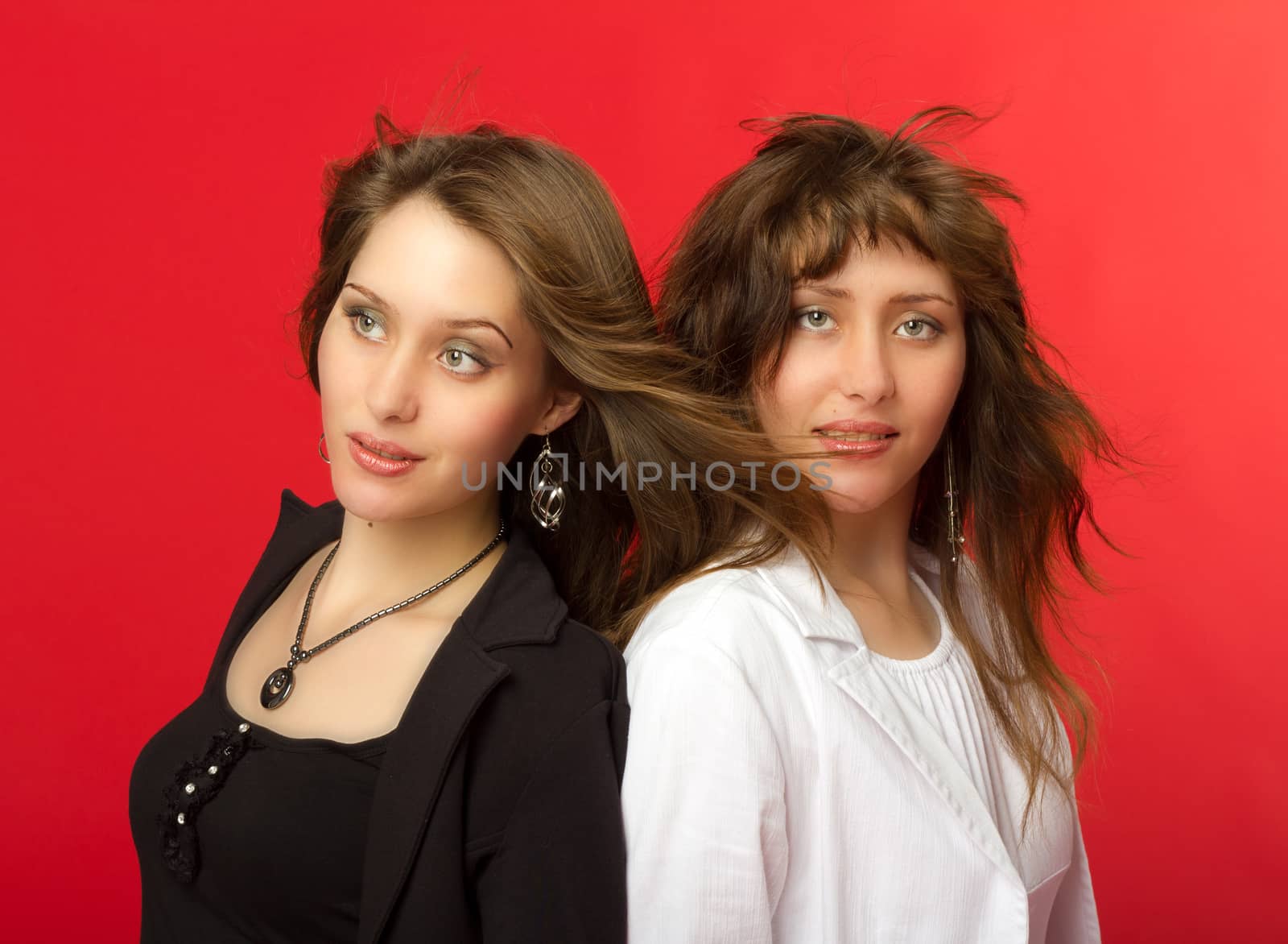 young pretty sisters twins portrait in studio on red background