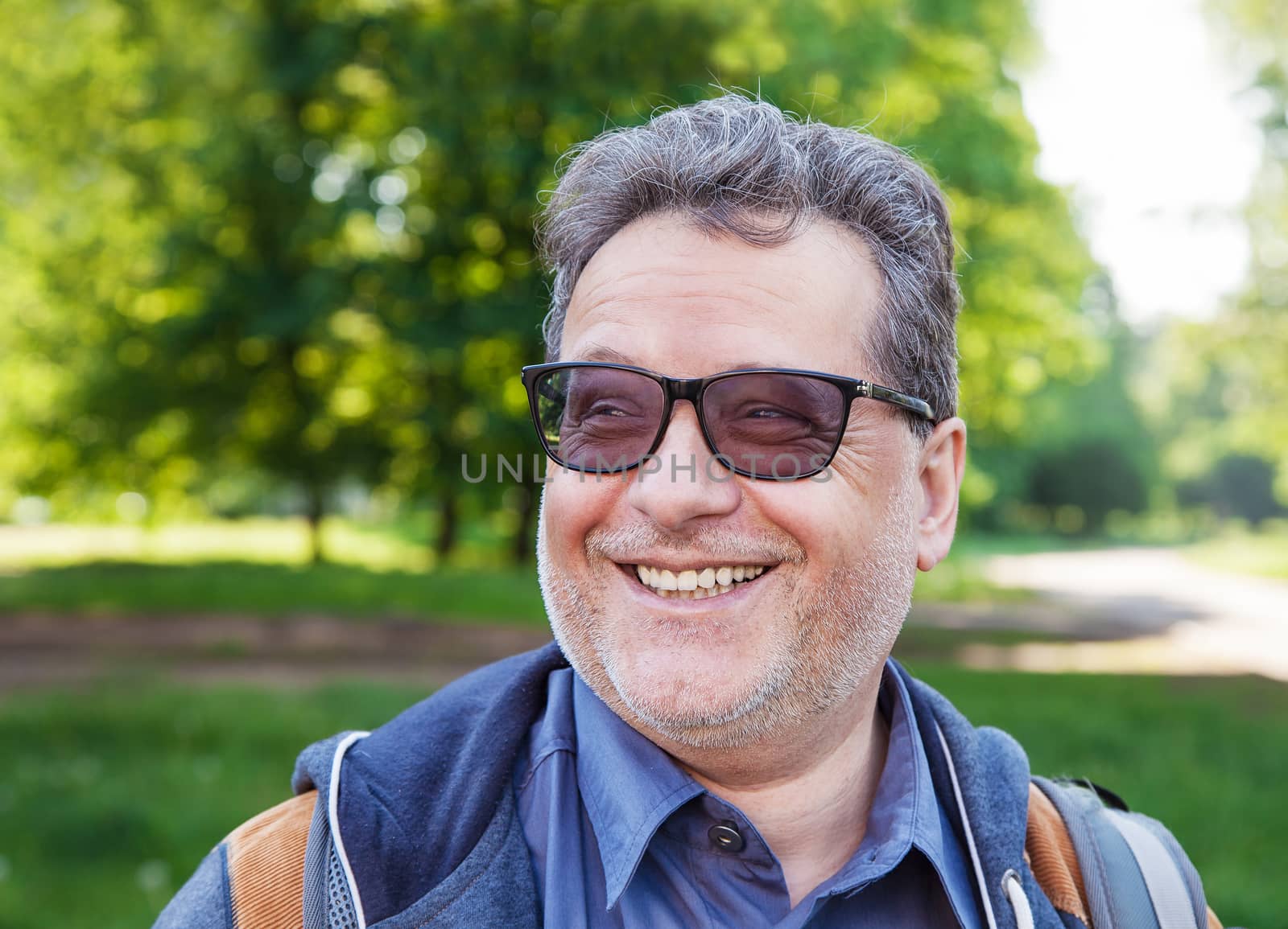 portrait of a smiling elderly man in park on summer day closeup