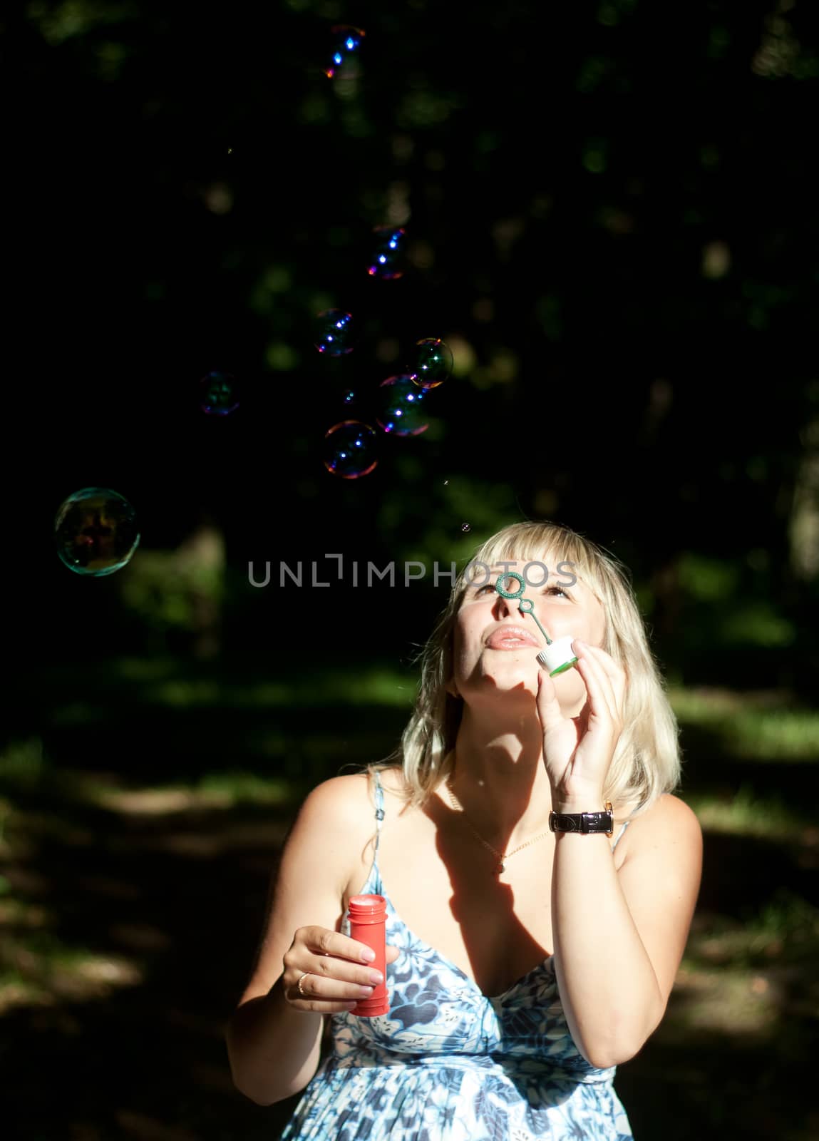 young pregnant woman blowing soap bubbles outdoor