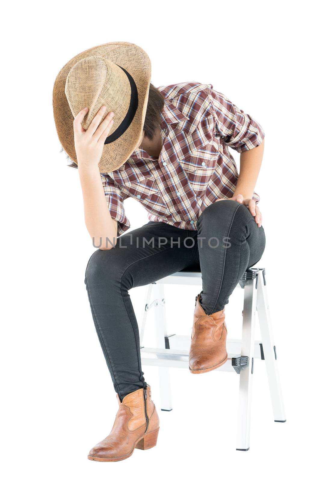 Young woman in a cowboy hat and plaid shirt with hand on her hat by stoonn