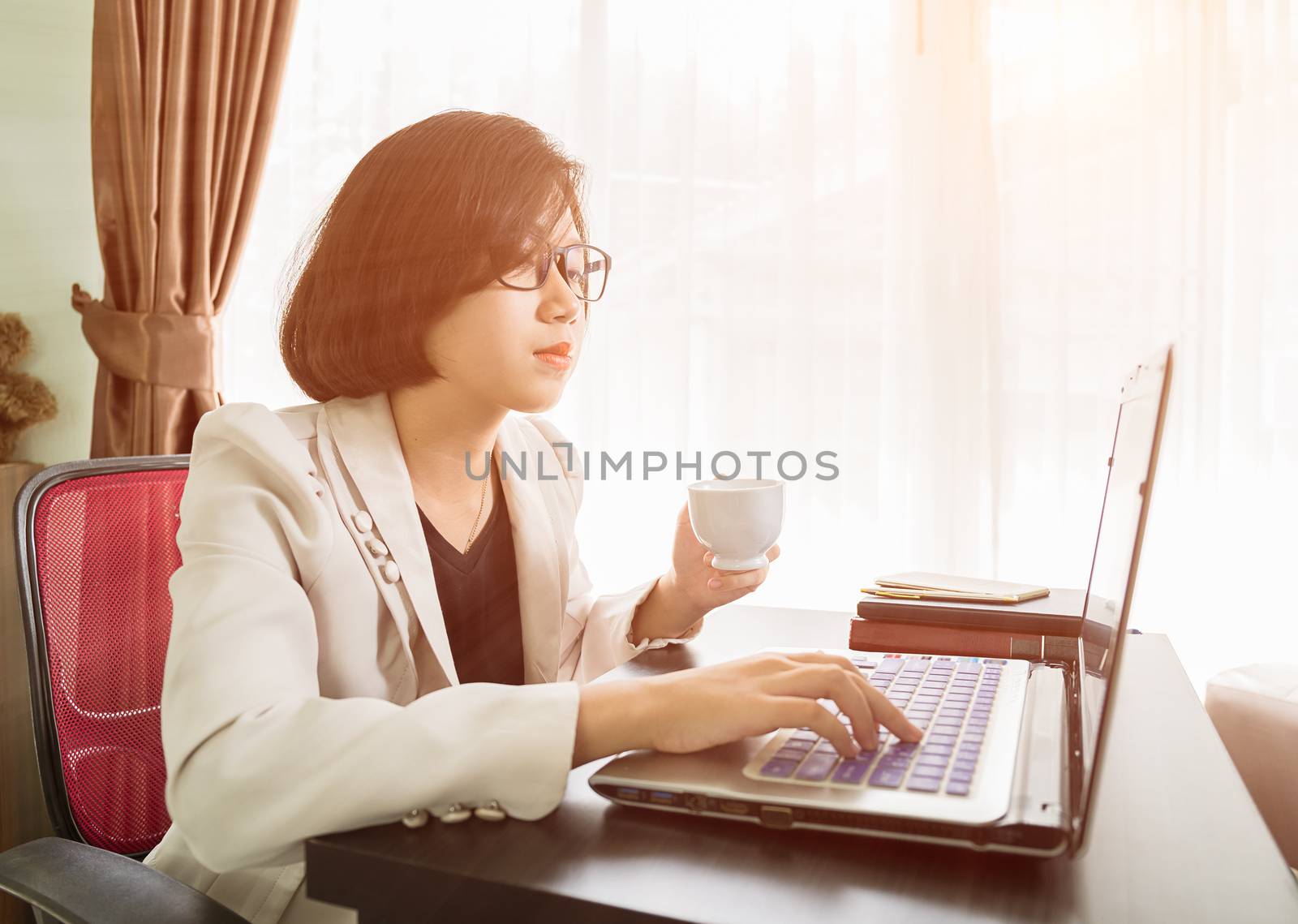 Woman teenage short hair in smart casual wear working on laptop while sit near window in home office