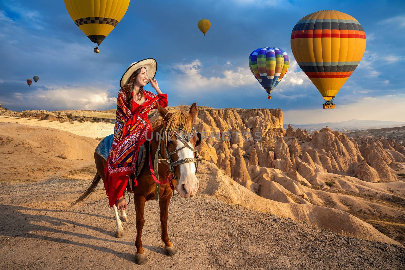 Tourists enjoy ride horses and looking to balloons in Cappadocia, Turkey