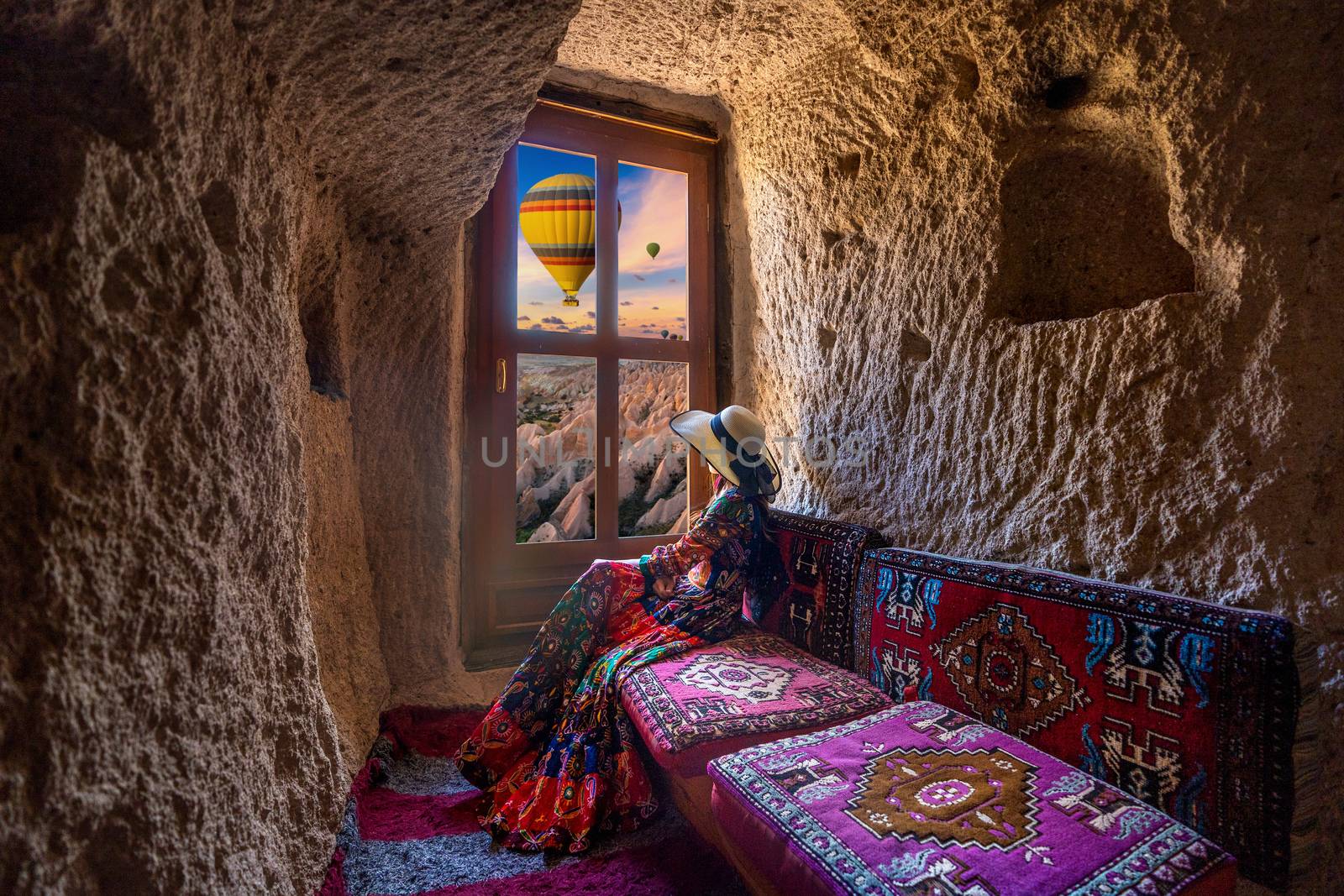 Woman sitting in cave house and looking to windows with beautiful scenic in Goreme, Cappadocia, Turkey. by gutarphotoghaphy