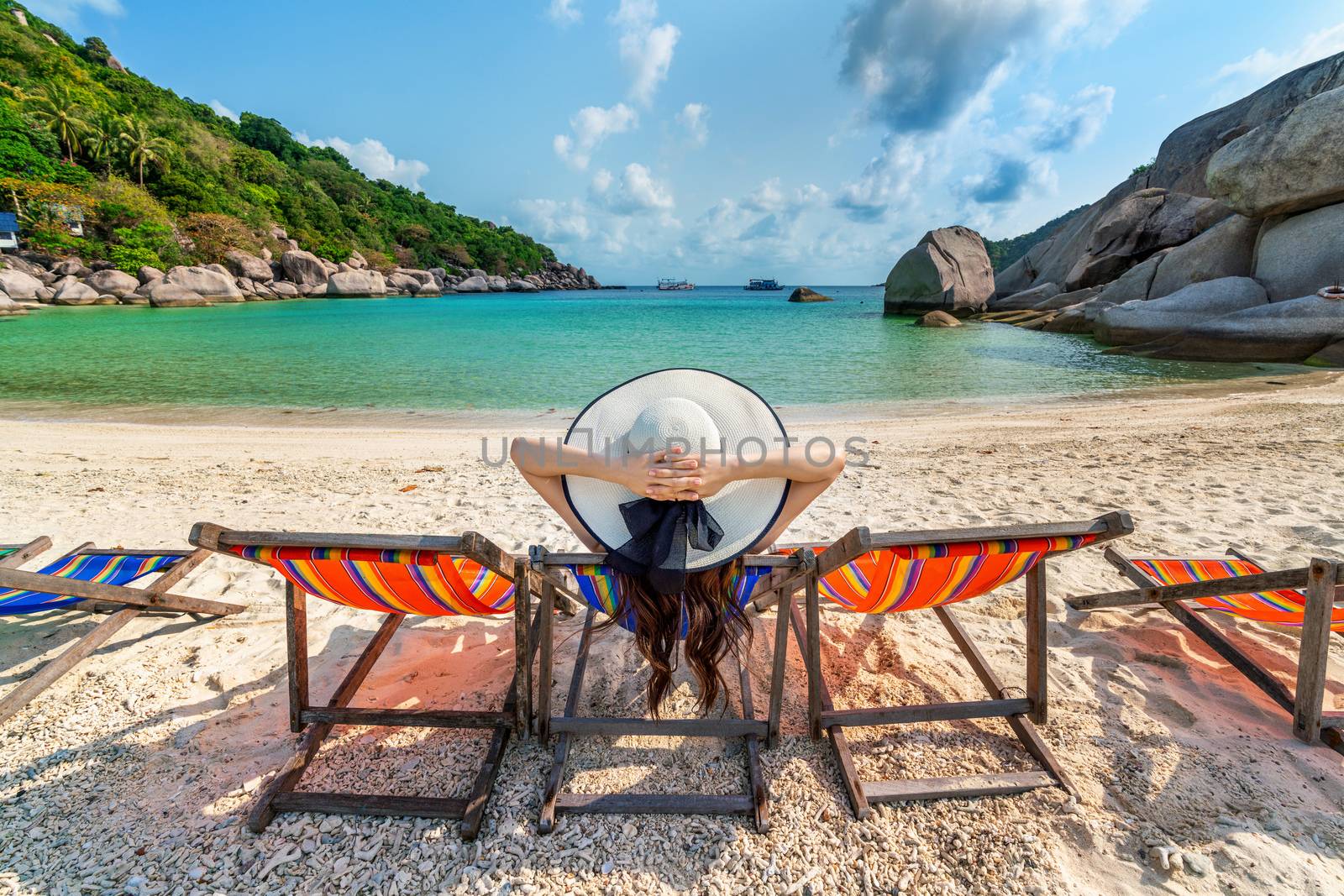 Woman with hat sitting on chairs beach in beautiful tropical beach. Woman relaxing on a tropical beach at Koh Nangyuan island. by gutarphotoghaphy