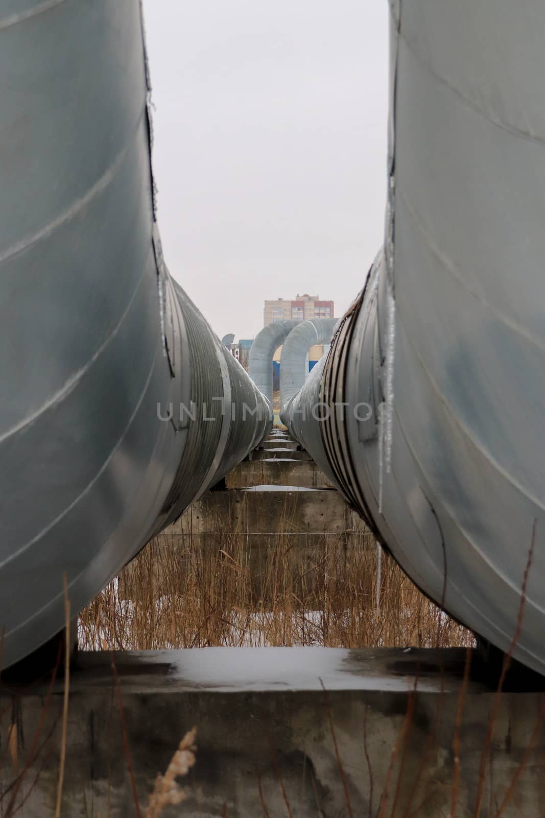 Two metal pipes with clearance departing into the distance background.Two metal pipes with clearance departing into the distance. House on background.