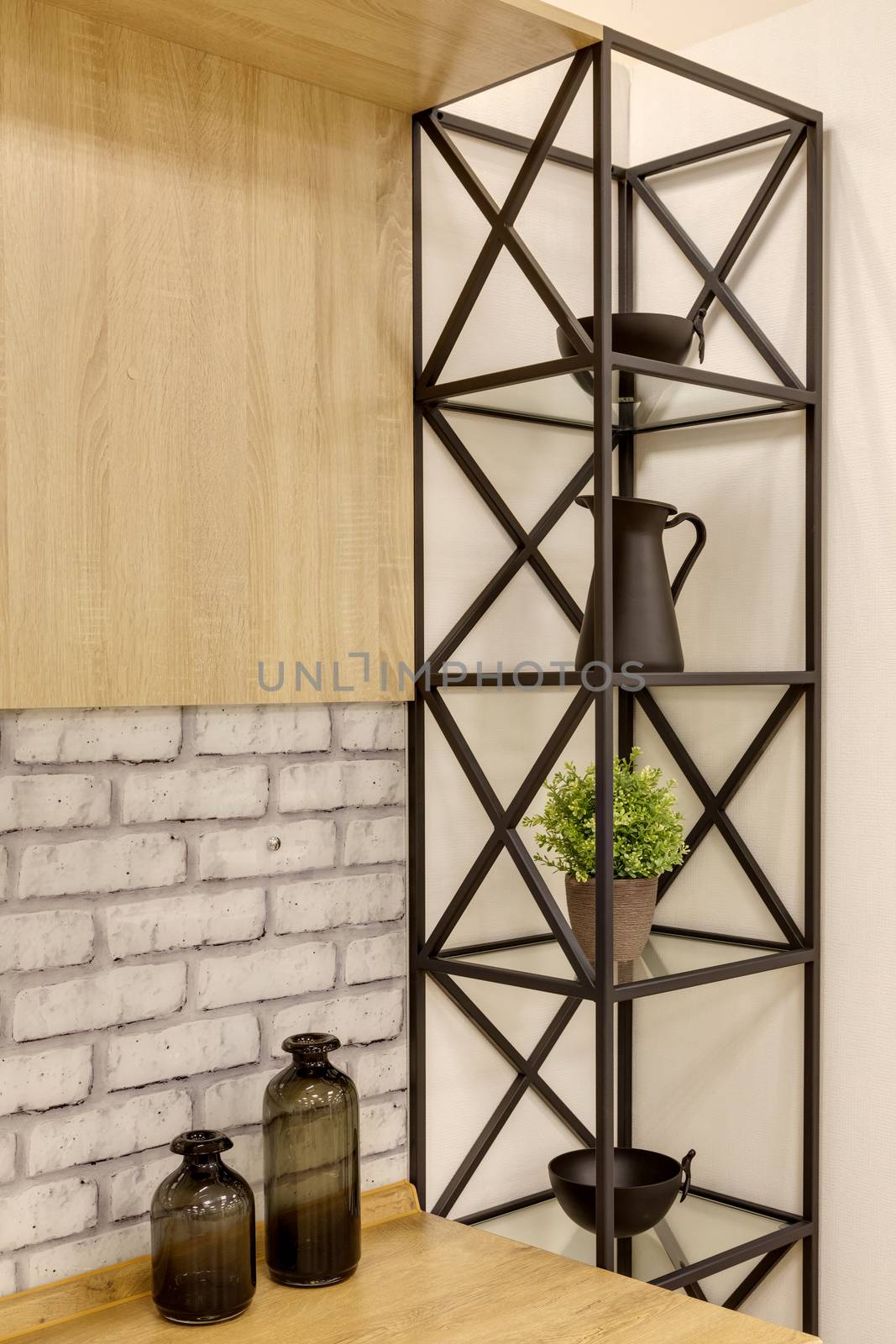 Fragment of a room with a metal black bookcase with shelves near the table