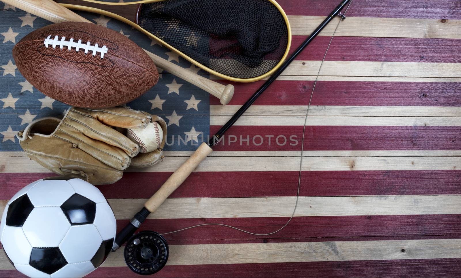 Various sport equipment for baseball, football, soccer and fishing on vintage wooden USA flag 