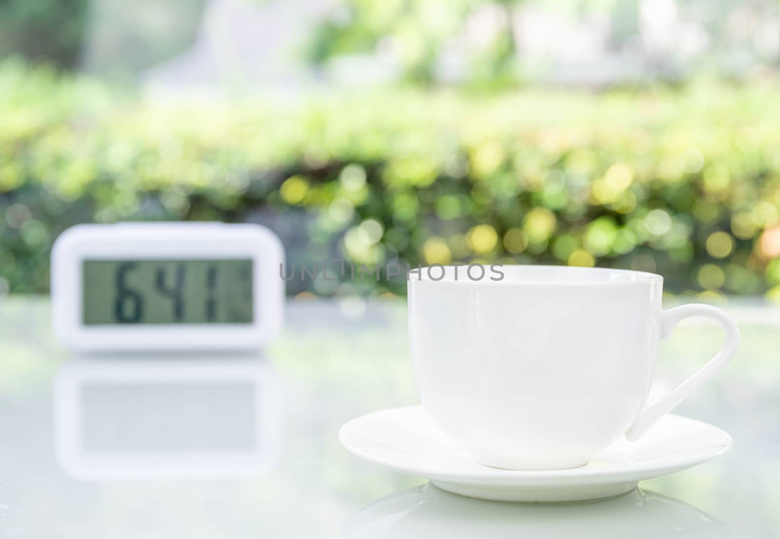 Coffee cup at office with digital clock by stoonn