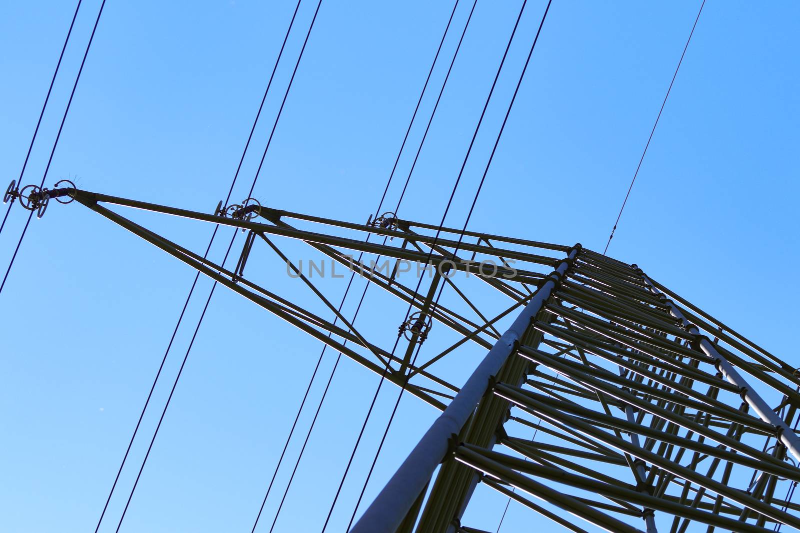 electricity pylons from low angle with blue sky by PeterHofstetter