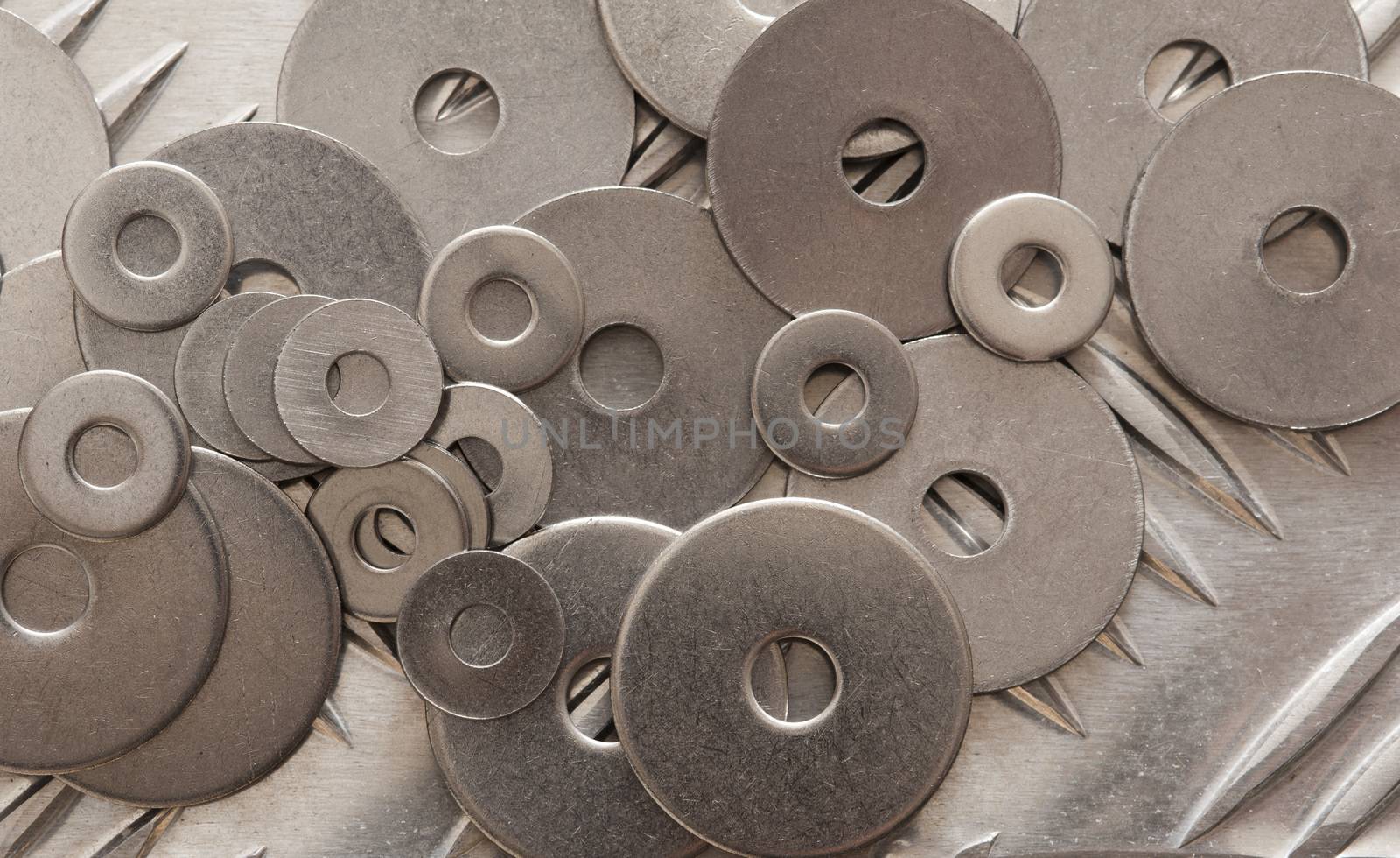 Scattered metal washers in a range of sizes on a not slip steel grid in an industrial or DIY background