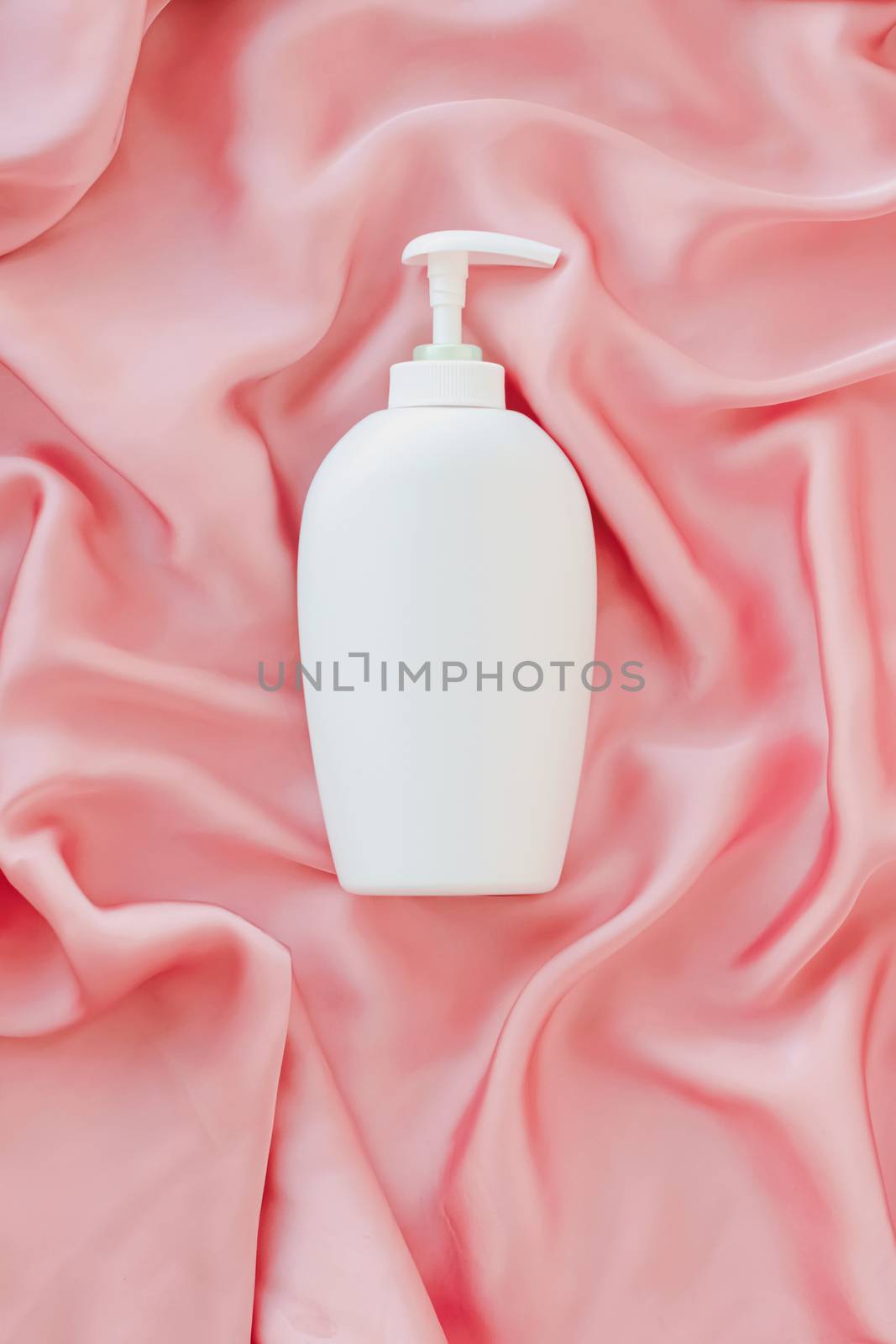 Blank label cosmetic container bottle as product mockup on pink silk background by Anneleven