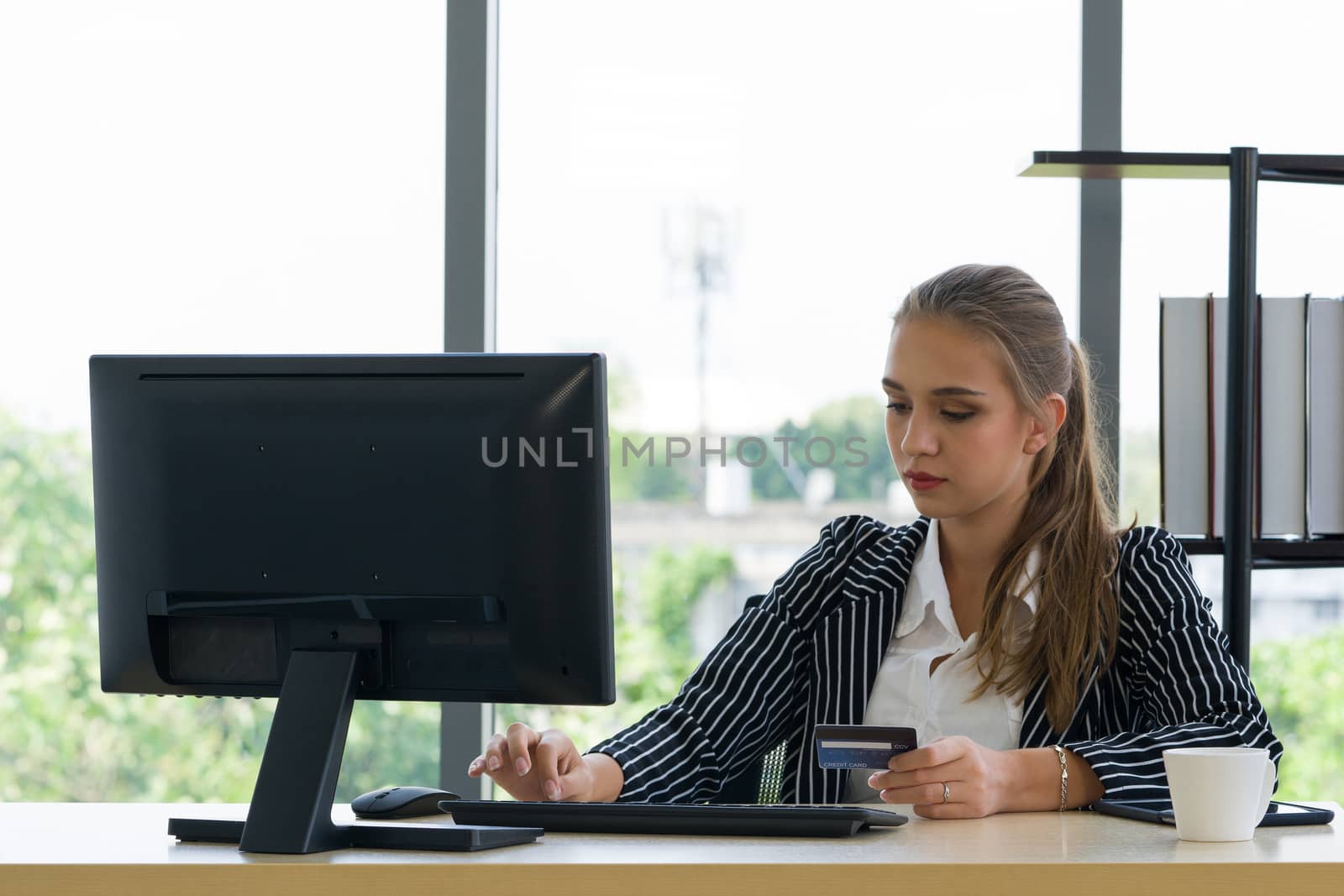 Teen employees spend time between coffee breaks to order products online. The shopper is filling in the credit card information for placing the order.