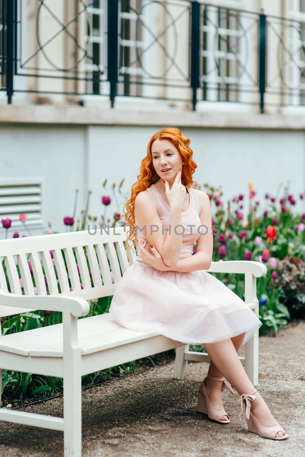 red-haired young girl walking in a park between trees and architectural objects