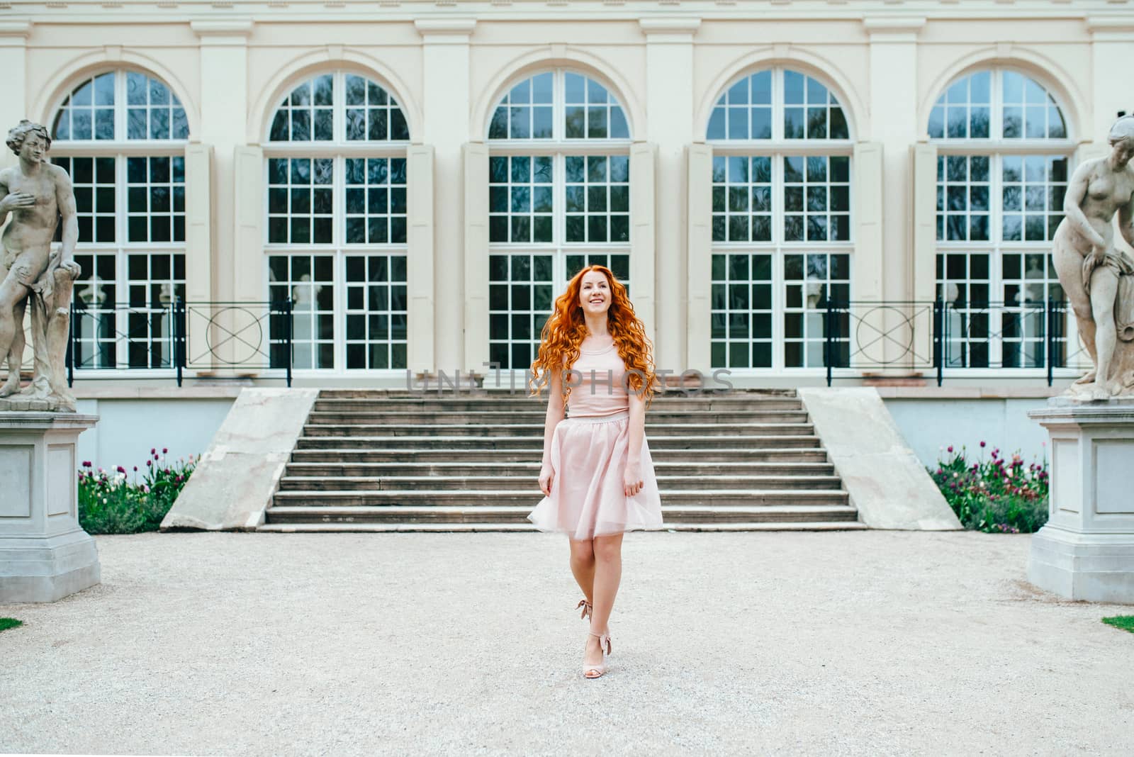 red-haired young girl walking in a park between trees by Andreua