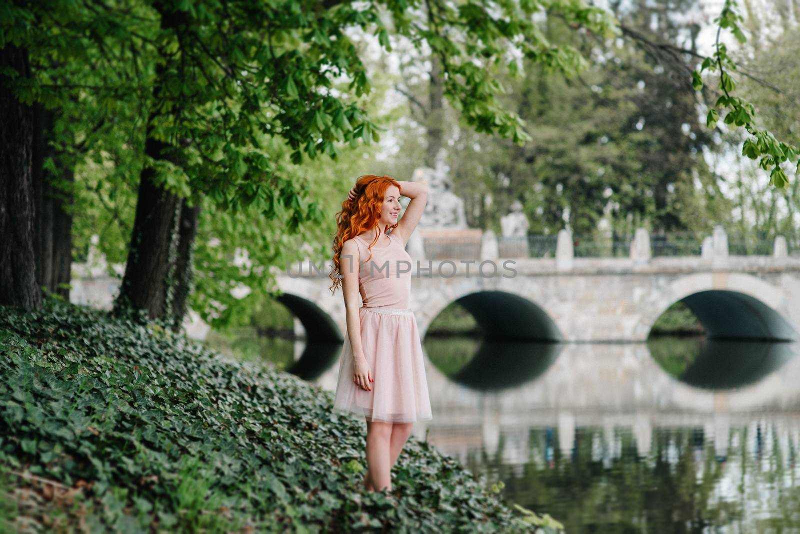 red-haired young girl walking in a park between trees by Andreua