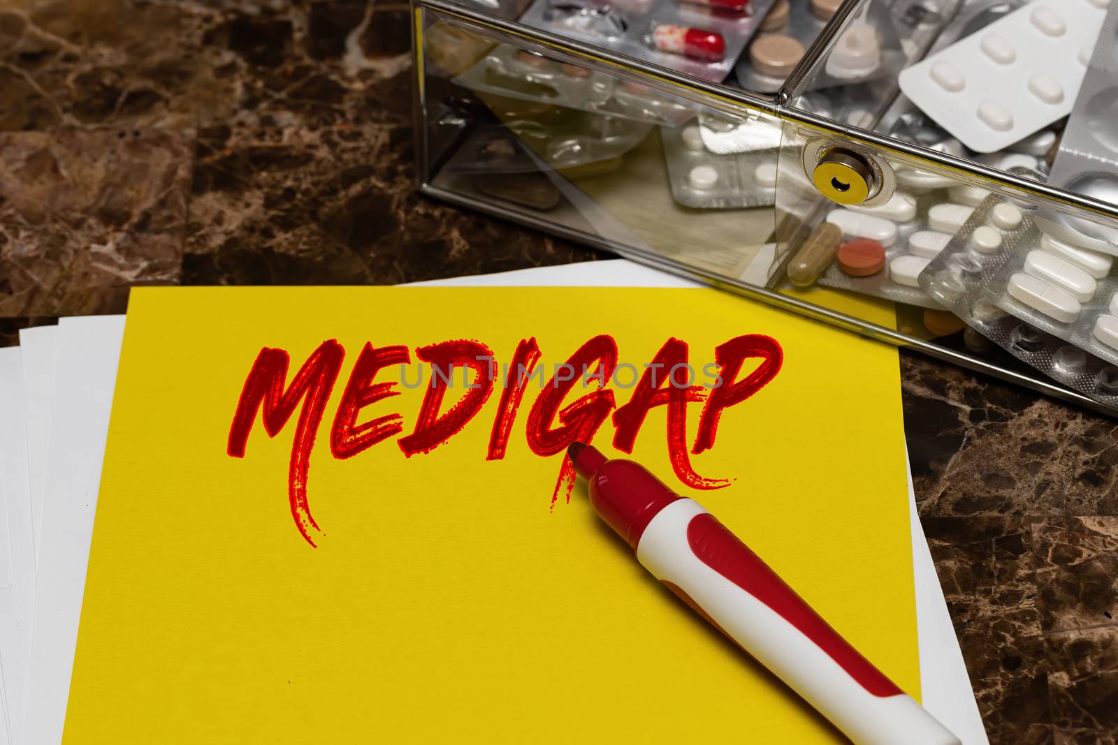 Medigap is written in red letters on a yellow sheet lying on the table next to a box of pills. Medical or healthcare concept