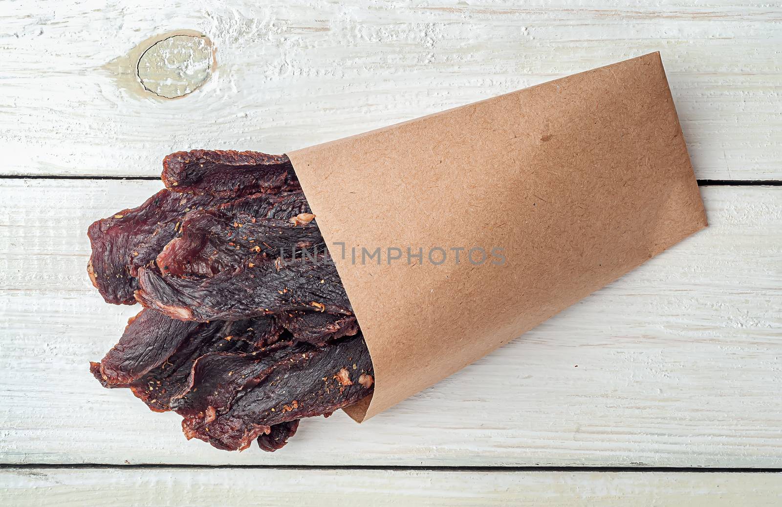 Jerky in a paper bag on top on a white table top view