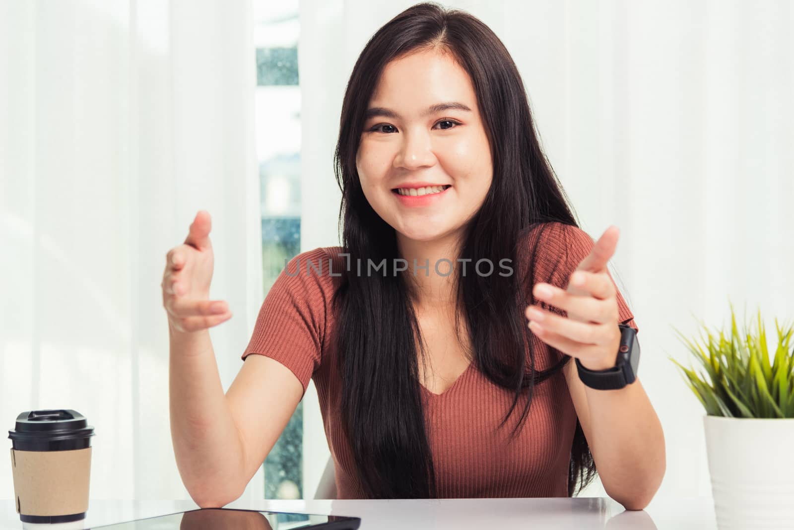 Work from home, Asian business young beautiful woman smiling sitting on desk workspace raise hand explain job communication with team video conferencing on digital tablet computer at home office