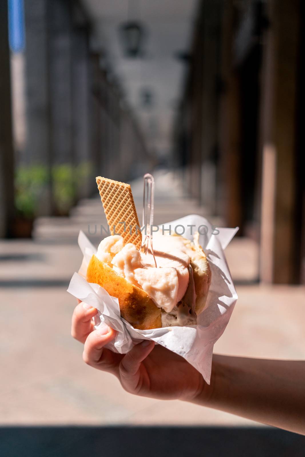 Young woman, tourist holding gelato or ice cream in brioche traditional Sicilian street food dessert in Palermo, Sicily, Italy.