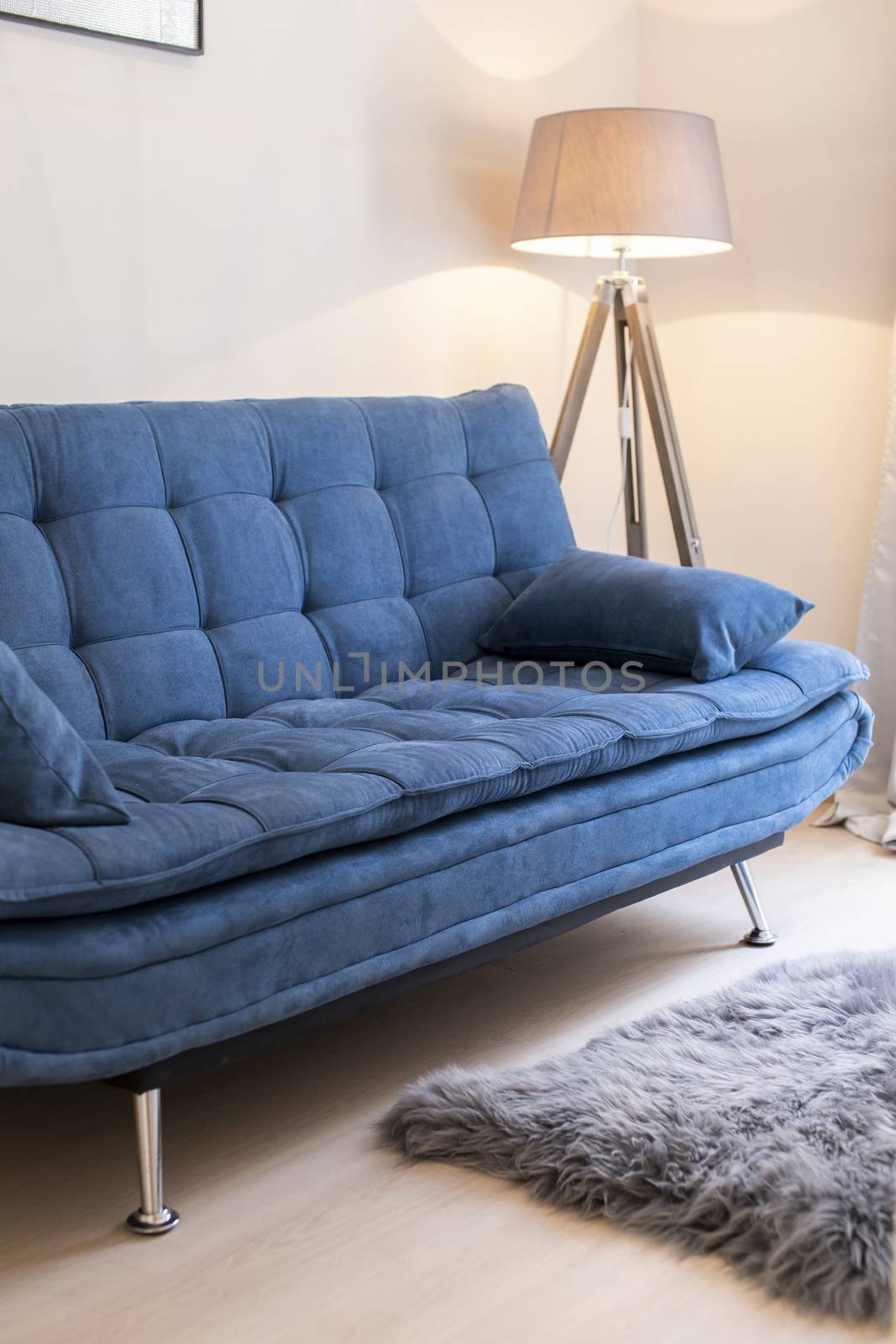 Comfy blue sofa and a standing lamp in a minimalist living space.