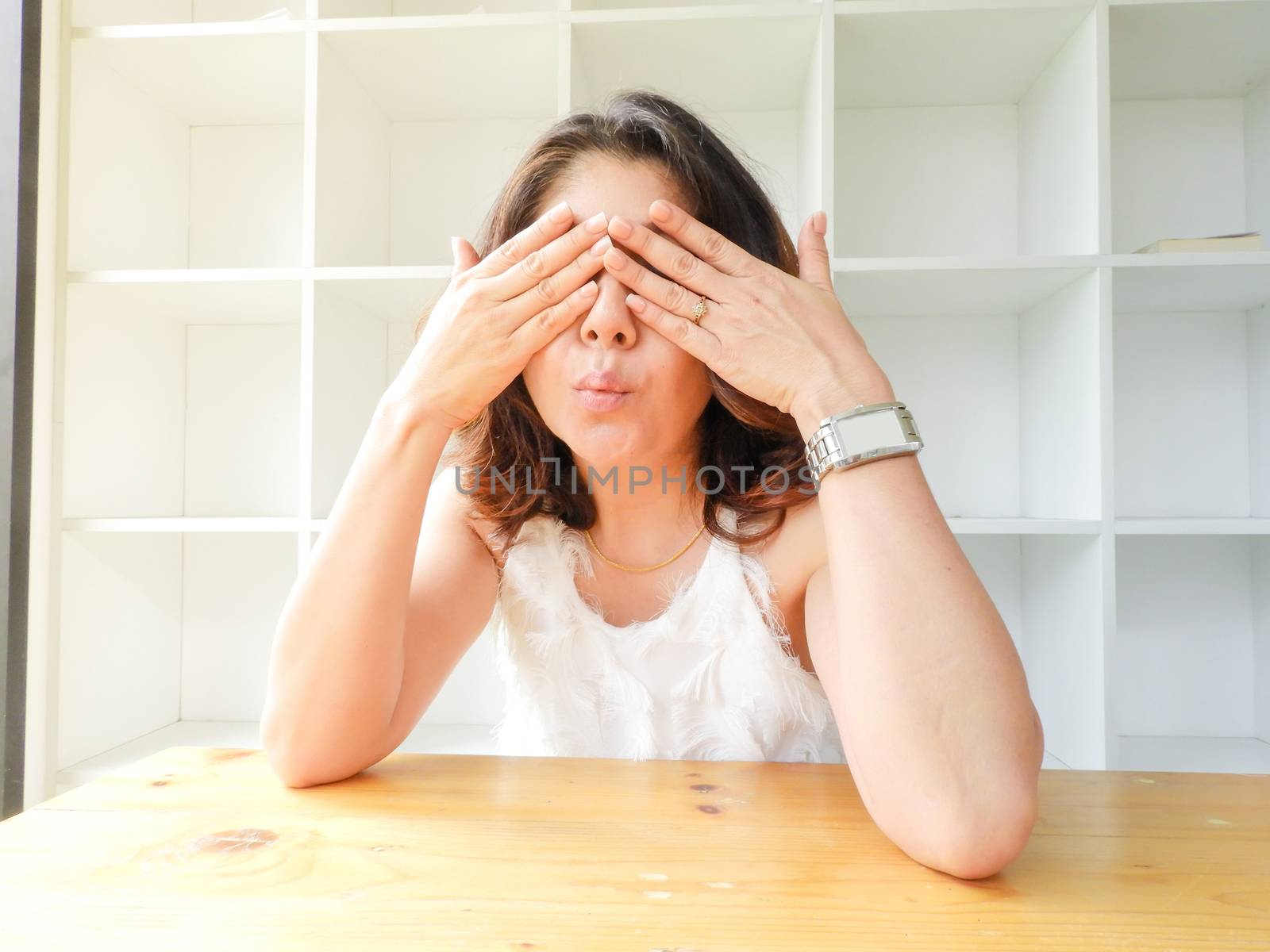 Beautiful woman closed her eyes against white background and the wood table.
