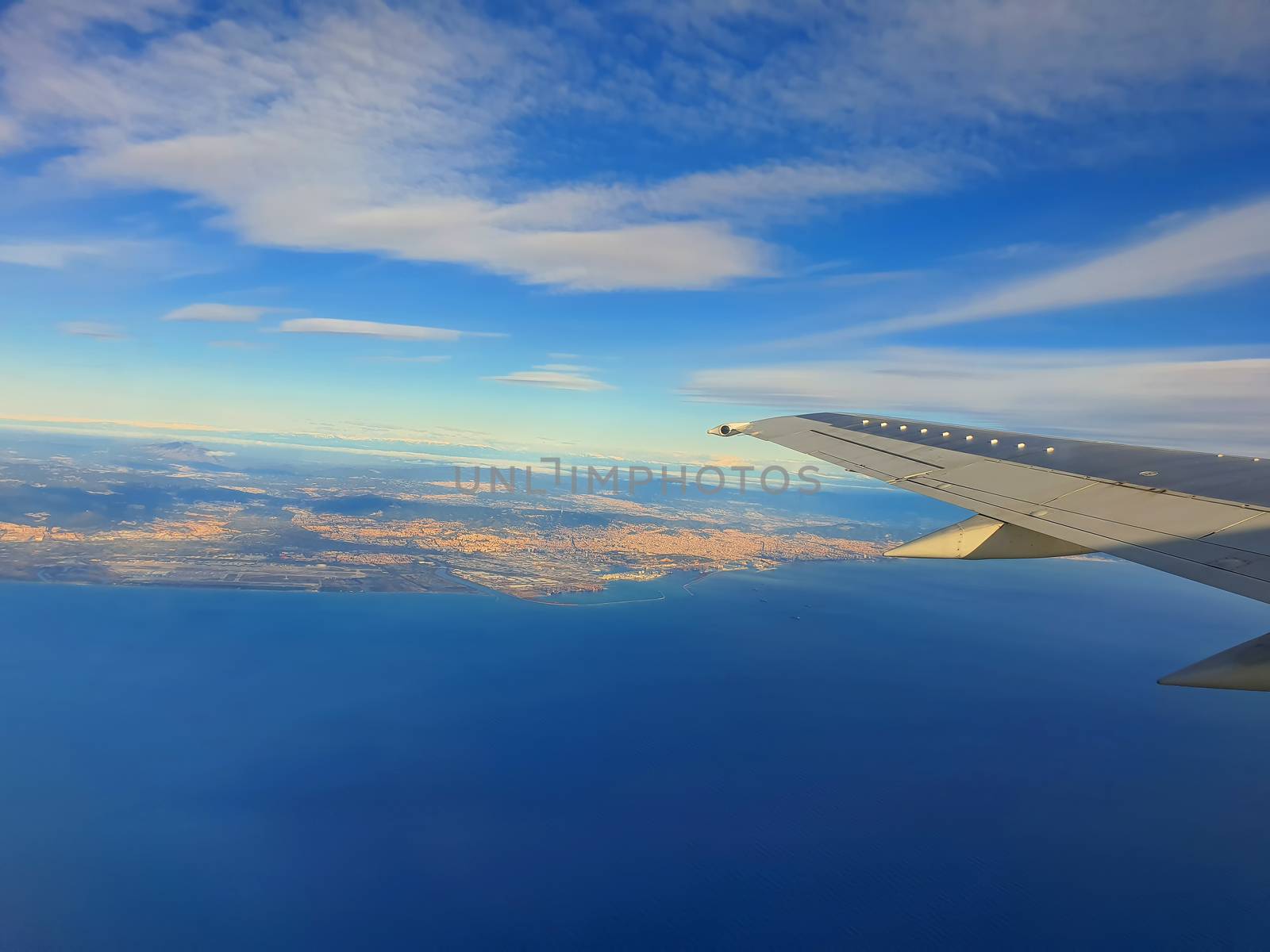 Airplane wing over sea and Barcelona cityscape
