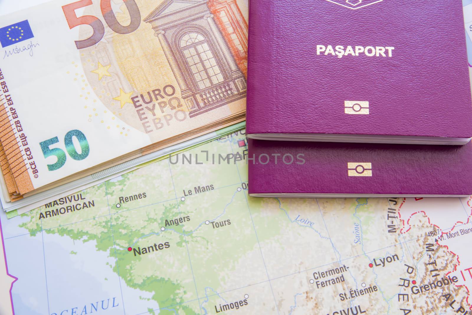 Euro banknotes and biometric passports over map.