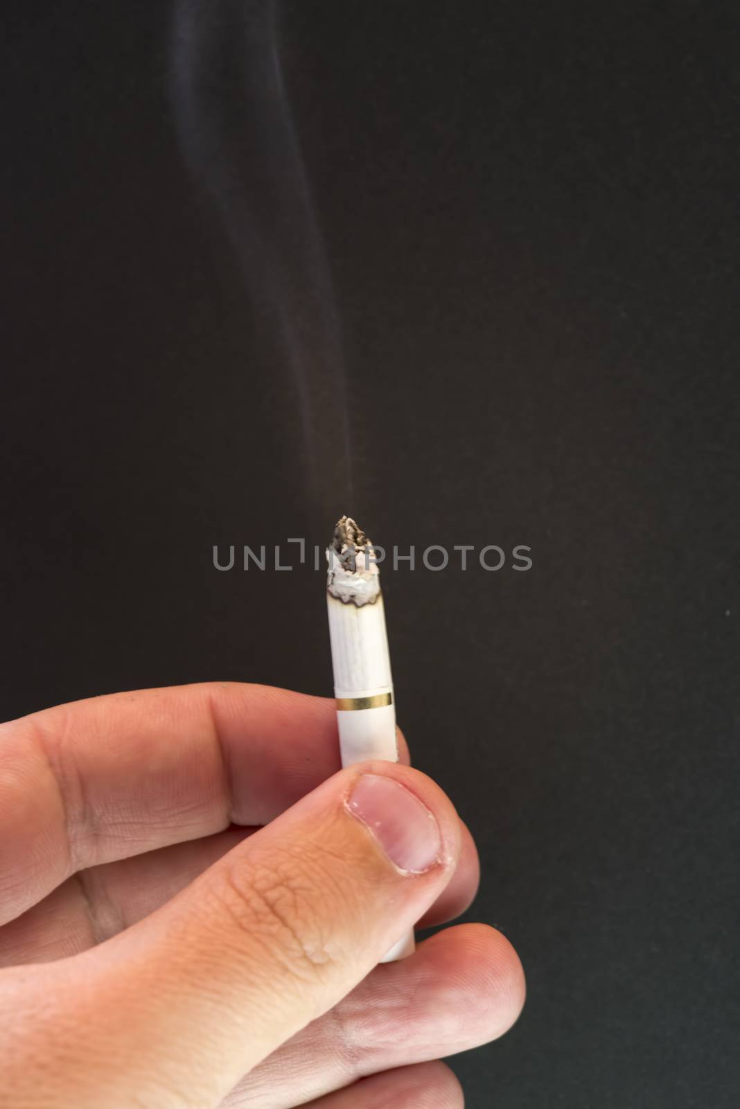 Burning cigarette and smoke over a dark background