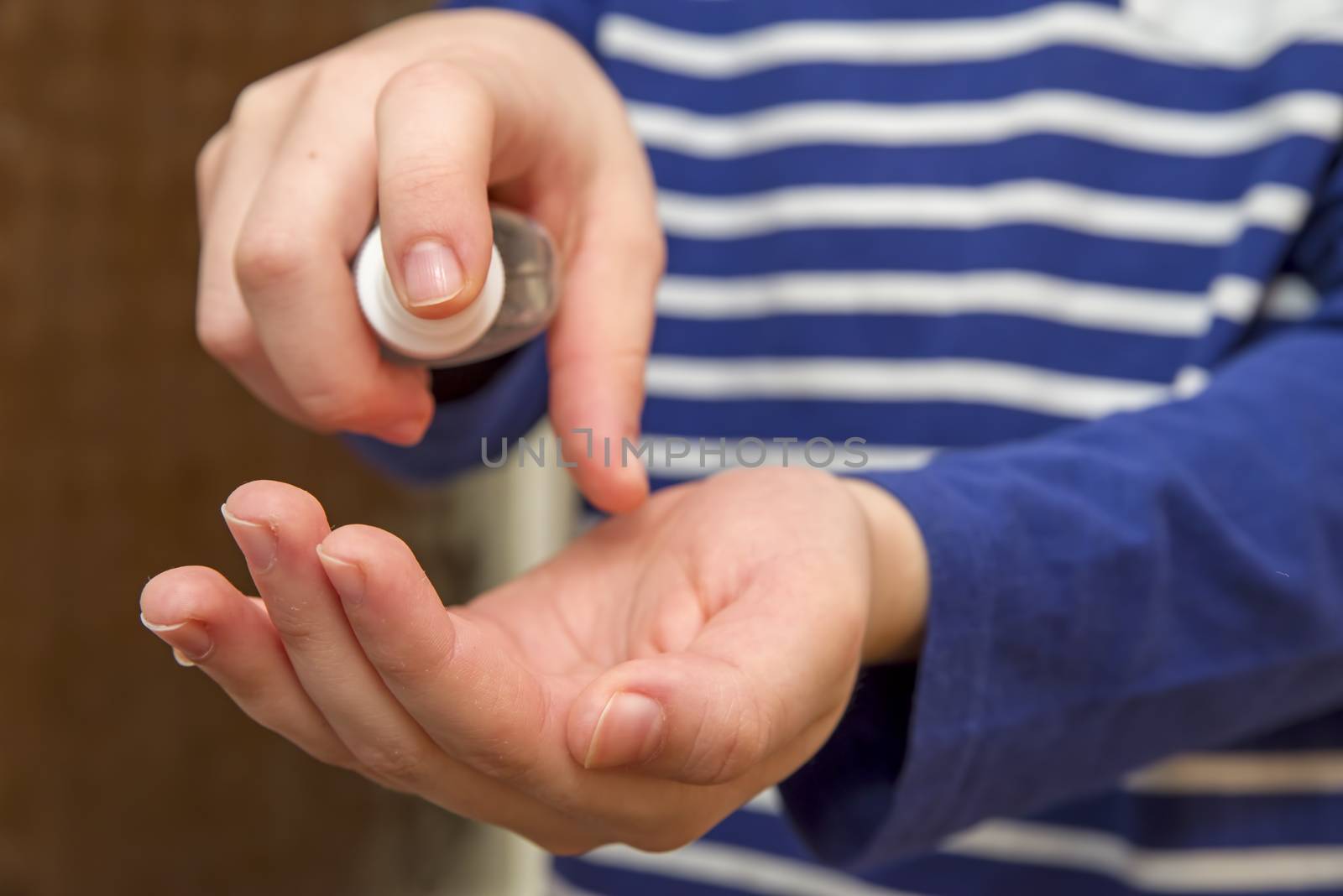 Kid wipes his hands with alcohol based spray, preventive measure against coronavirus