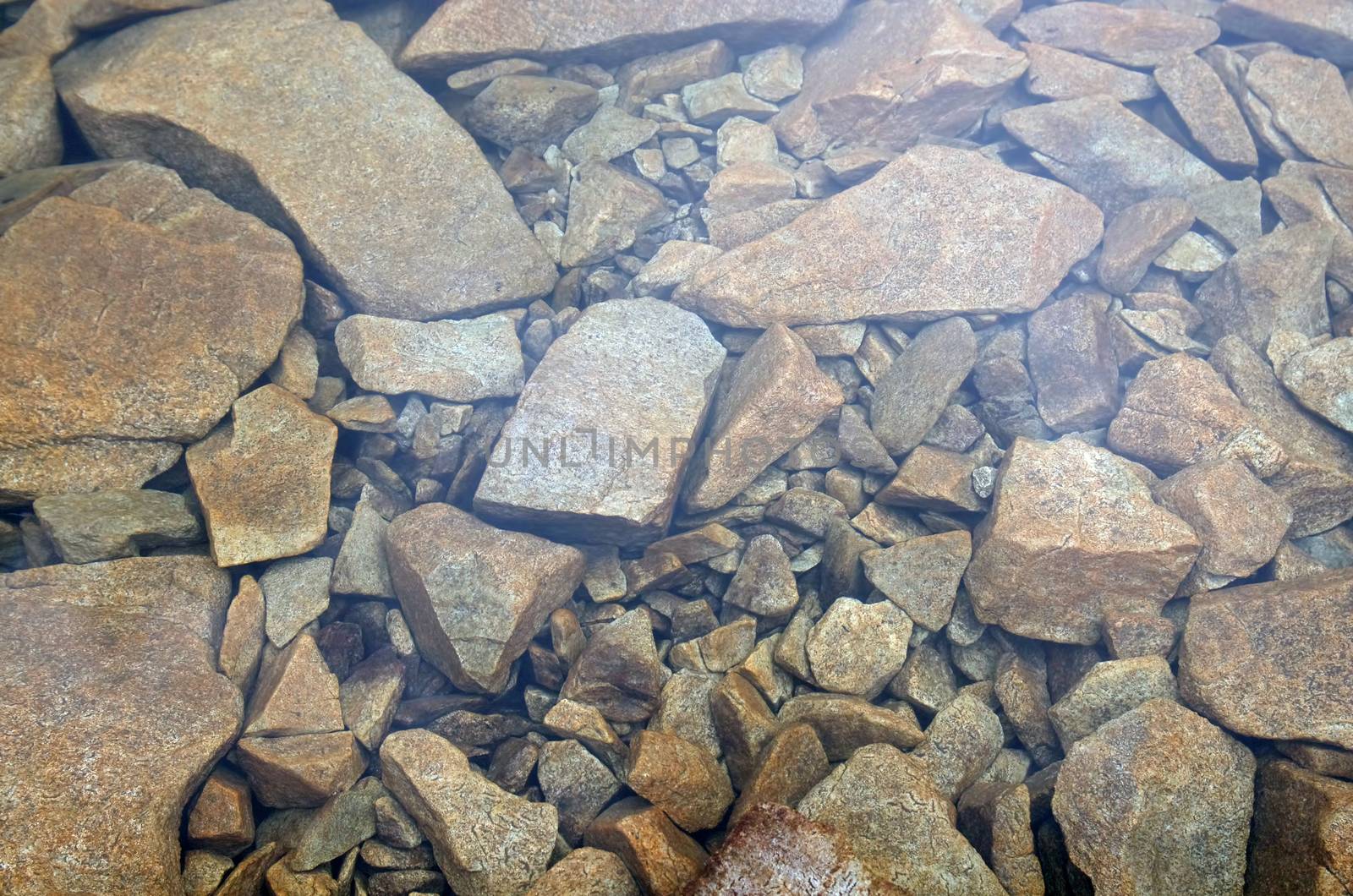 Stones under the clear water of a mountain lake in Romanian Carpathians.