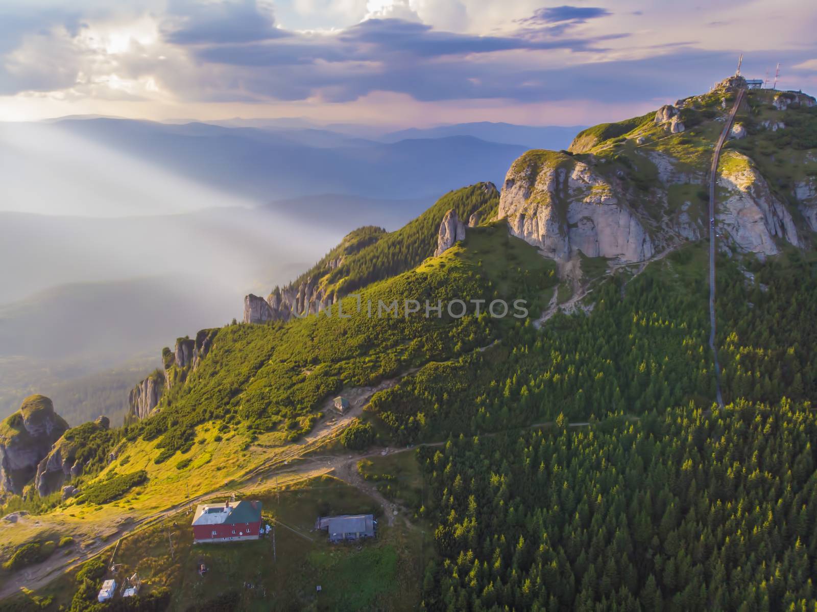 Aerial view of mountain chalet and peak stairs at sunset in Romanian Carpathians.