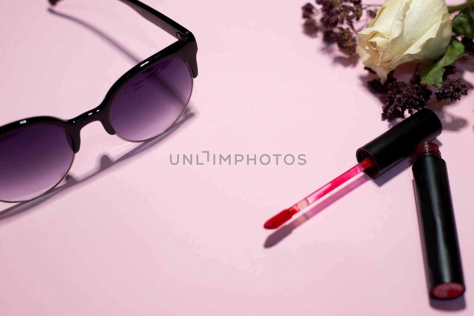 Sunglasses and cosmetics on a pink background