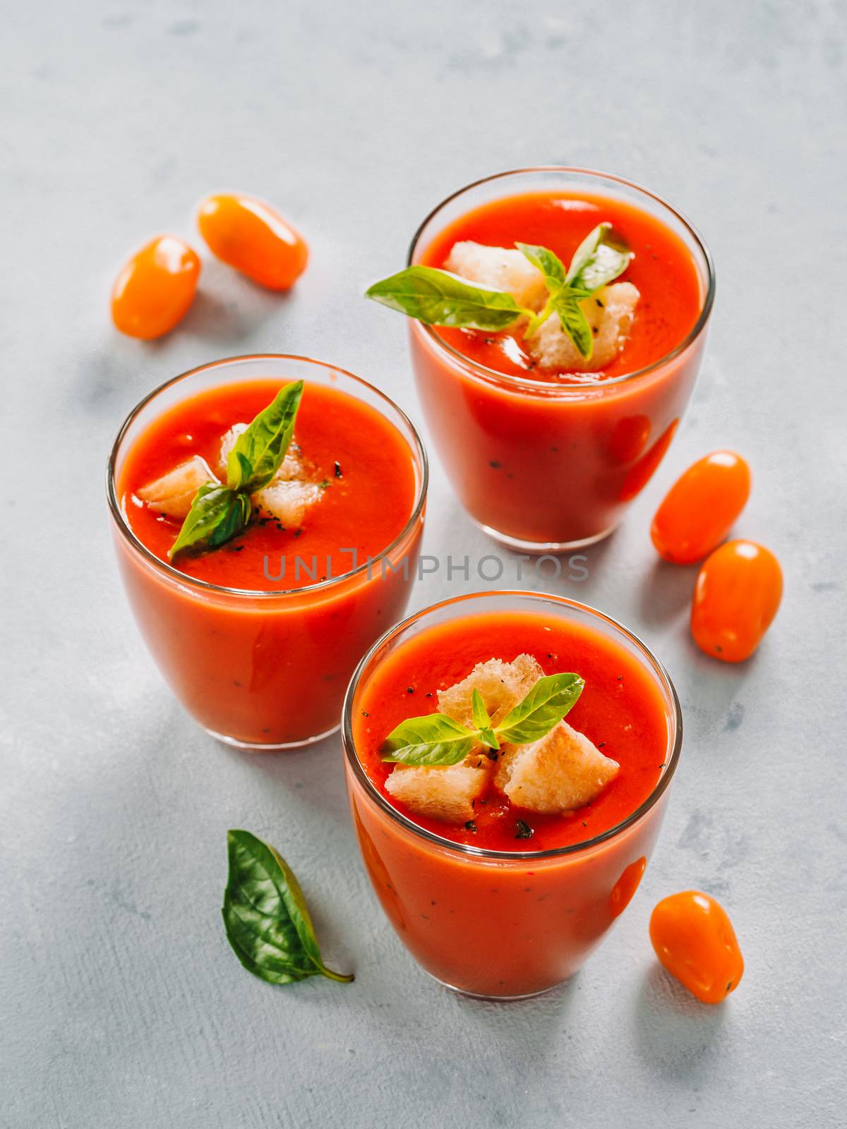 Delicious gaspacho soup in glass. Traditional spanish cold soup puree gaspacho or gazpacho on gray cement background. View from above or top view or flat lay. Vertical.