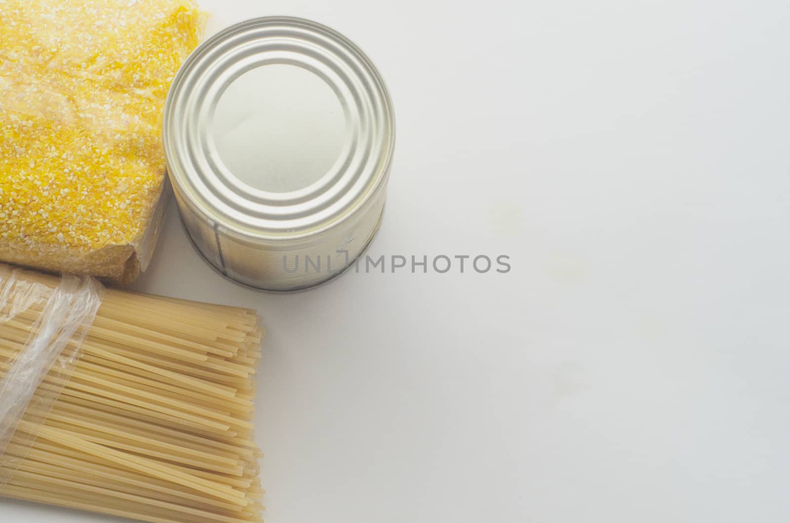Food supplies, crisis food stock for quarantine isolation period on white background. Pasta, corn grits and canned food. Food delivery, coronavirus quarantine. Copyspace.