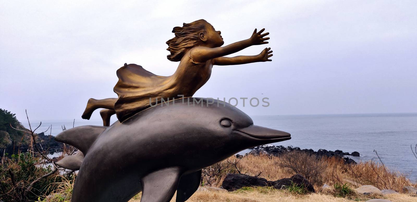 A girl statue with outstretched arms with a dolphin underneath in Jeju Island, South Korea by mshivangi92