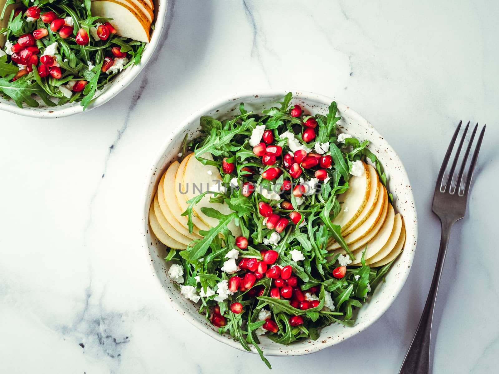 Vegan salad bowl with arugula, pear, pomegranate, cheese by fascinadora